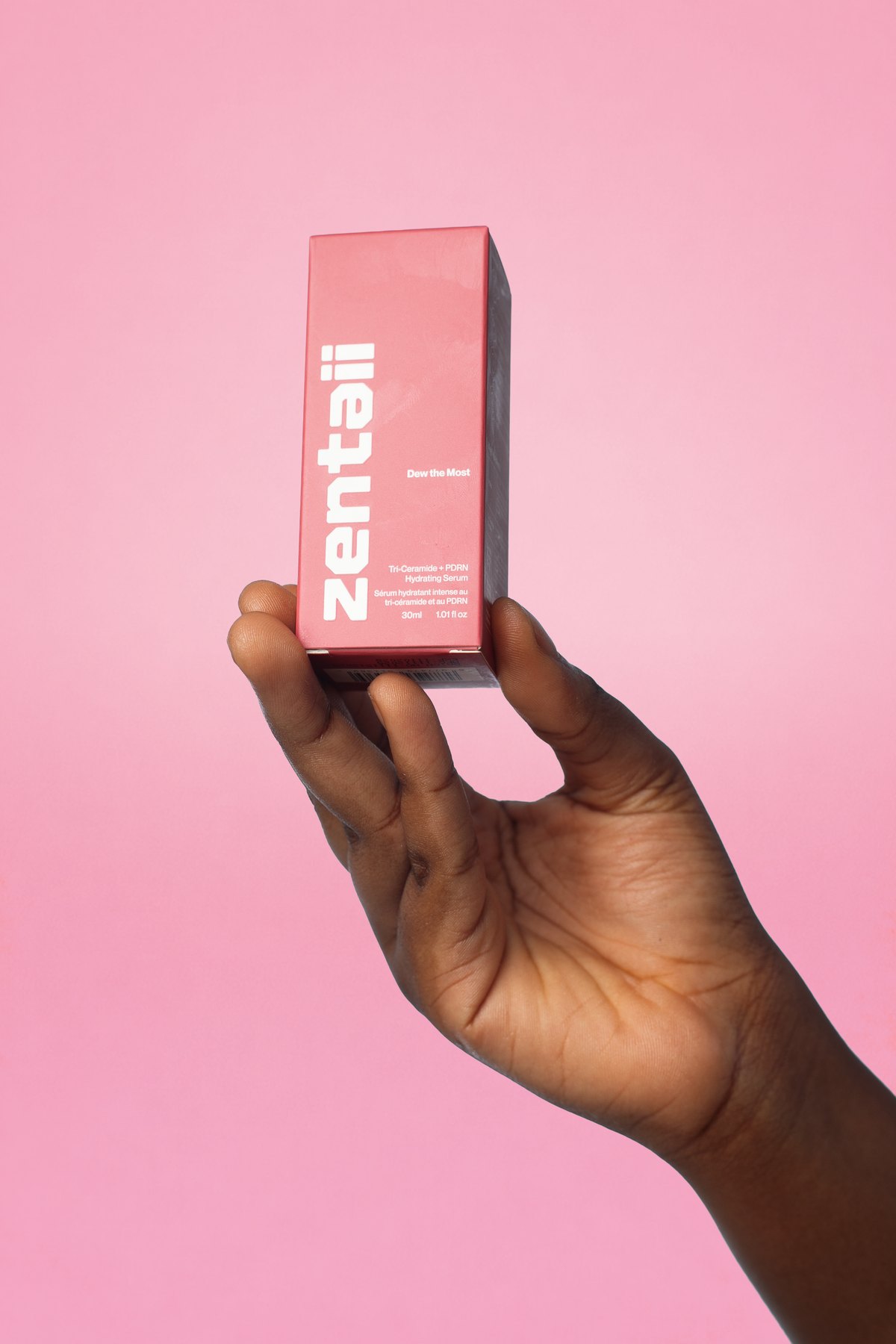 A hand holding the pink carton against a matching pink background.